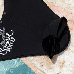 Zwarte Mermaid Sisters Pro Monovin met logo, ligt op een lichtgekleurde ondergrond naast water. Perfect voor zeemeerminzwemme