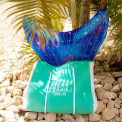 Grote turquoise sporttas van Mermaid Sisters met een zeemeermin staart in de achtergrond, perfect voor avonturen.
